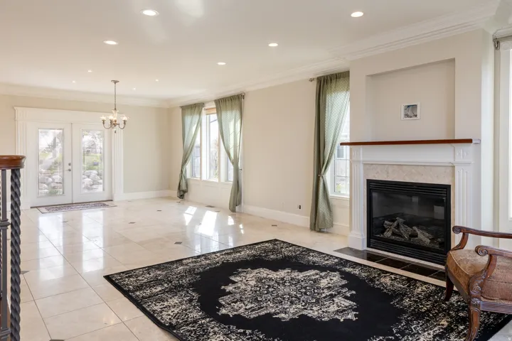 Living room with crown molding, hanging lights, a fireplace with flush hearth, light tile patterned flooring, and french doors