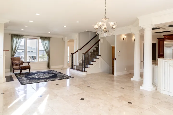 Foyer entrance featuring decorative columns, ornamental molding, and hanging lights