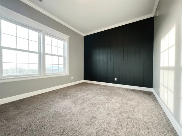 Unfurnished room with an accent wall, ornamental molding, and light carpet