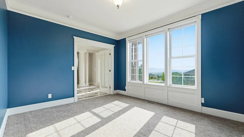 Carpeted room with blue painted walls, crown molding, and white window trim