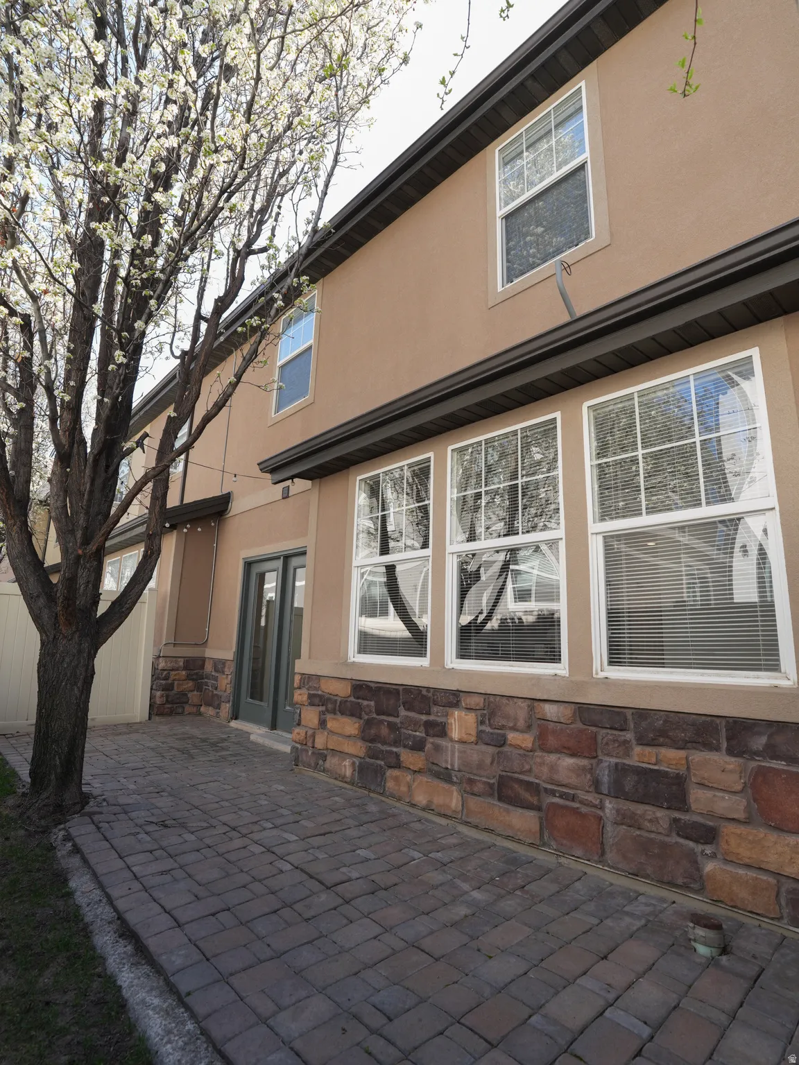 Rear view of property featuring stone siding, stucco siding, and a patio area