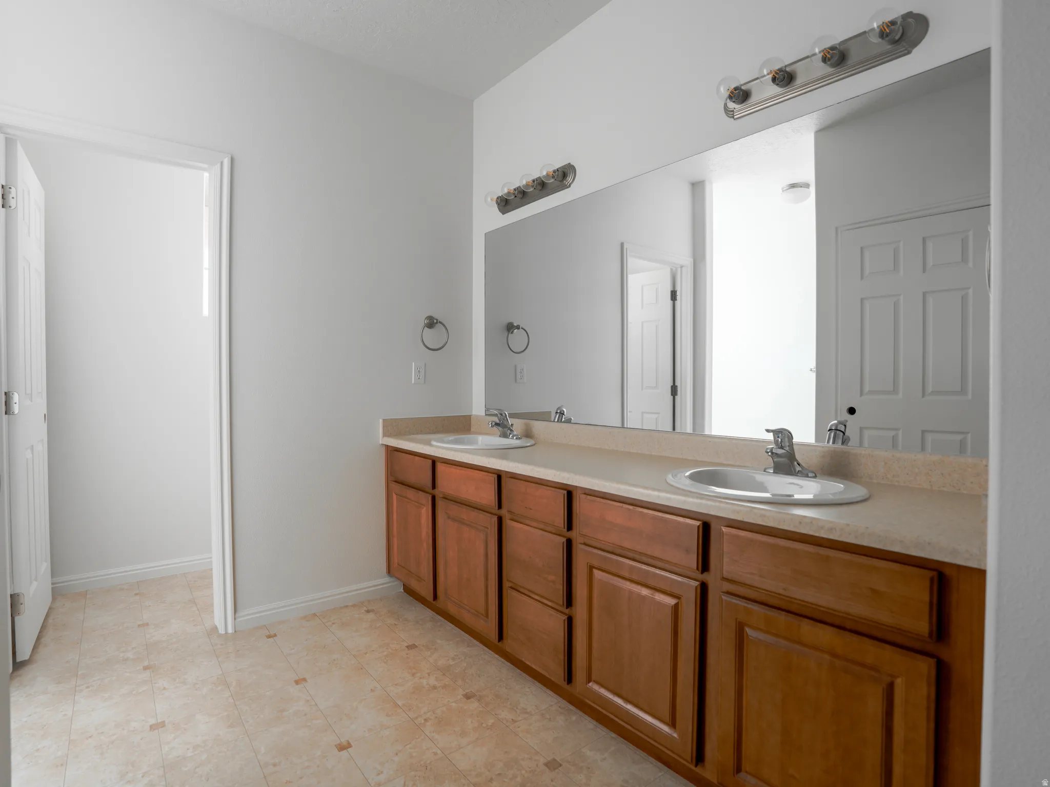 Full bath featuring double vanity and baseboards