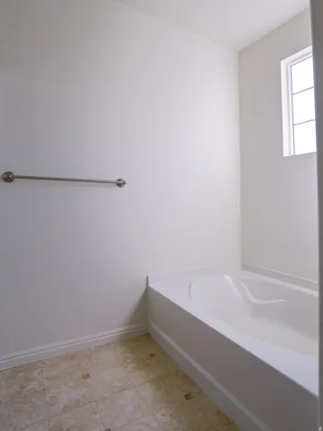 Bathroom with a bath and baseboards