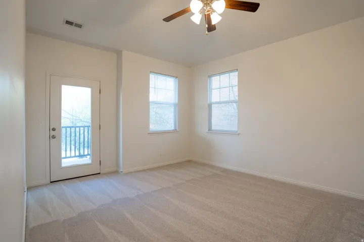 Spare room featuring light colored carpet, a ceiling fan, and plenty of natural light