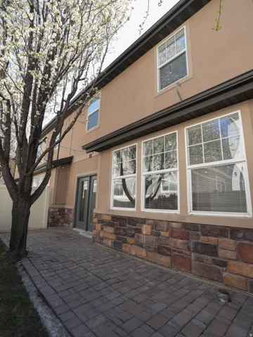 Rear view of property featuring stone siding, stucco siding, and a patio area