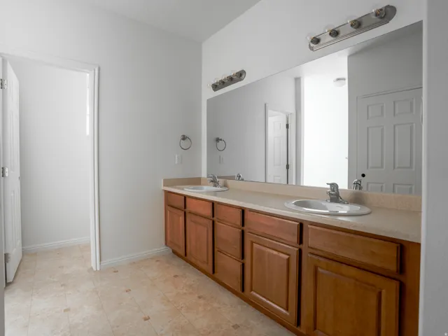 Full bath featuring double vanity and baseboards