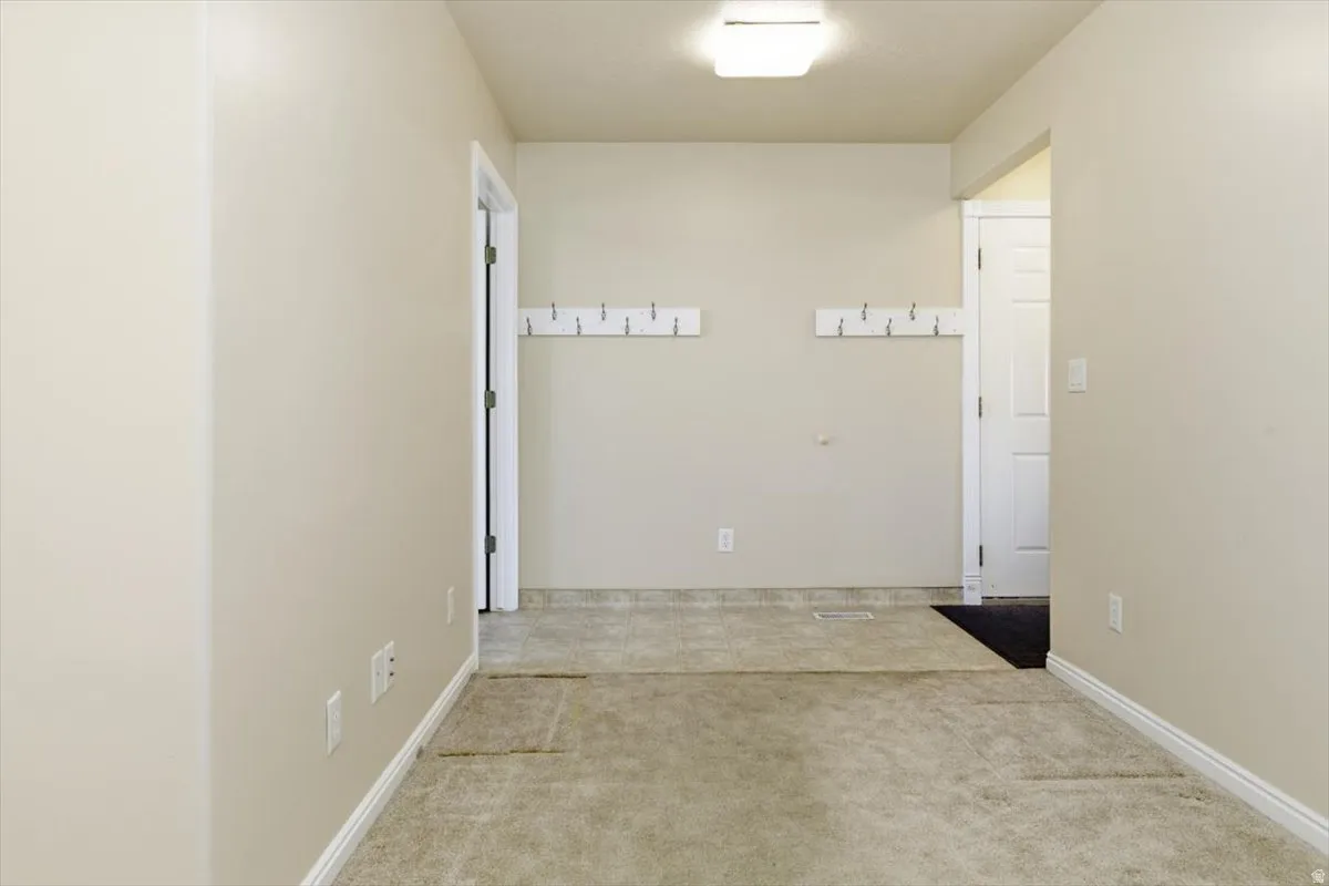 Hallway with light colored carpet and baseboards