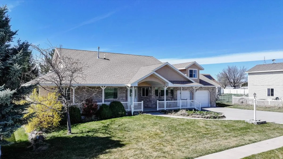 View of front of house featuring a porch, driveway, a garage, and a shingled roof