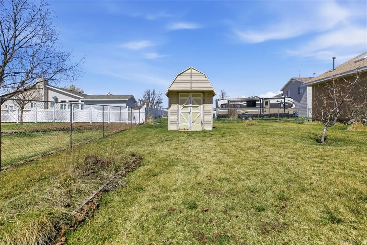 Fenced backyard featuring a storage unit