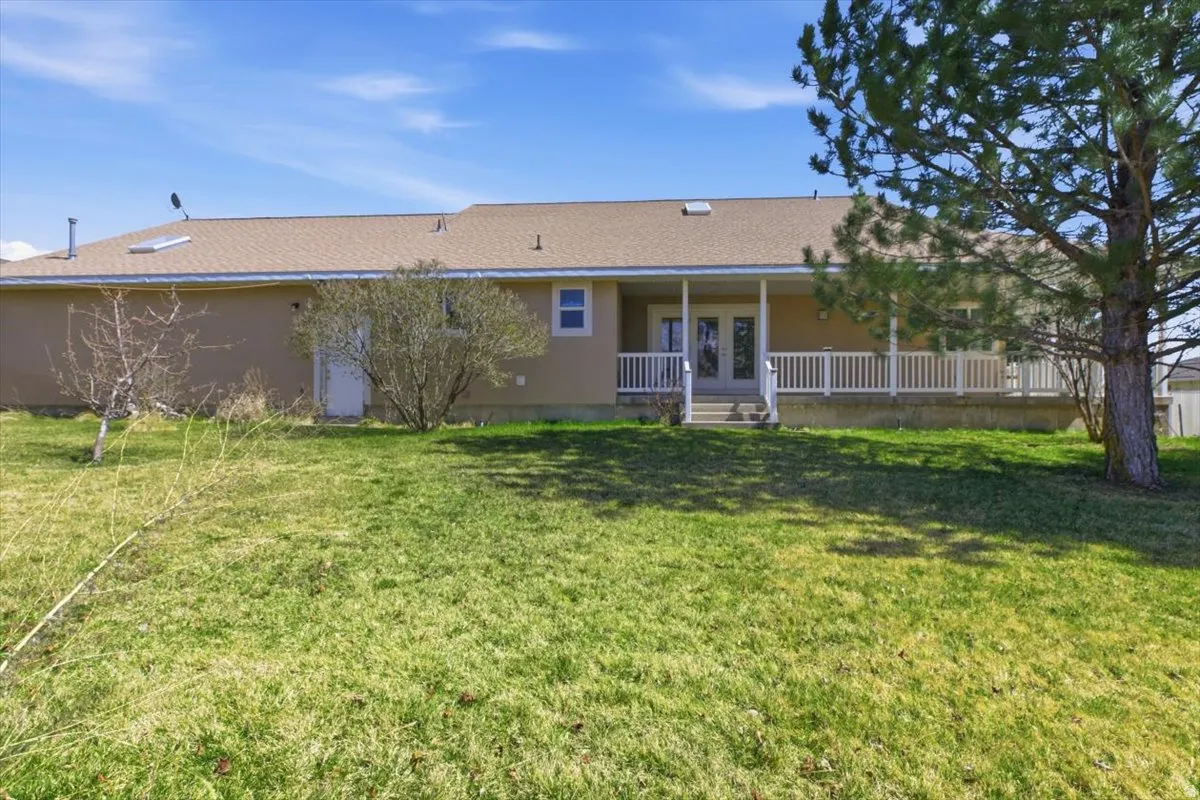 Back of house featuring french doors, a porch, and a yard