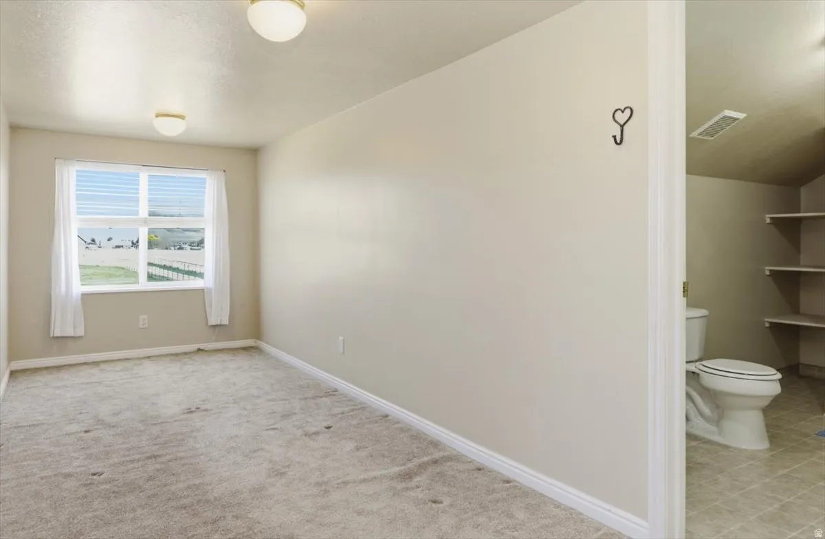 Empty room featuring baseboards and light carpet