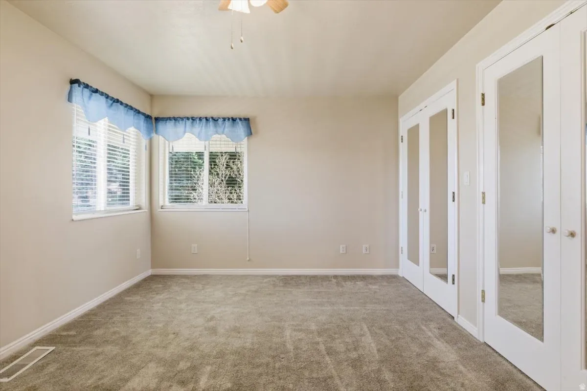 Spare room featuring french doors, carpet flooring, and a ceiling fan