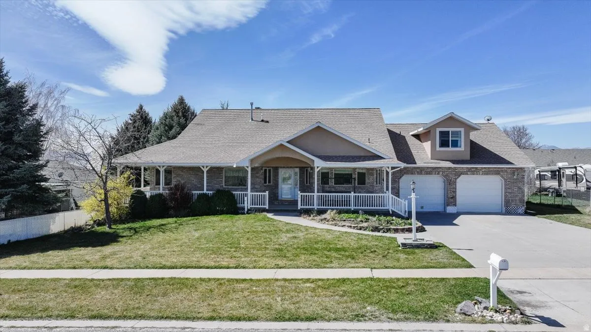View of front facade with a porch, driveway, a shingled roof, an attached garage, and brick siding