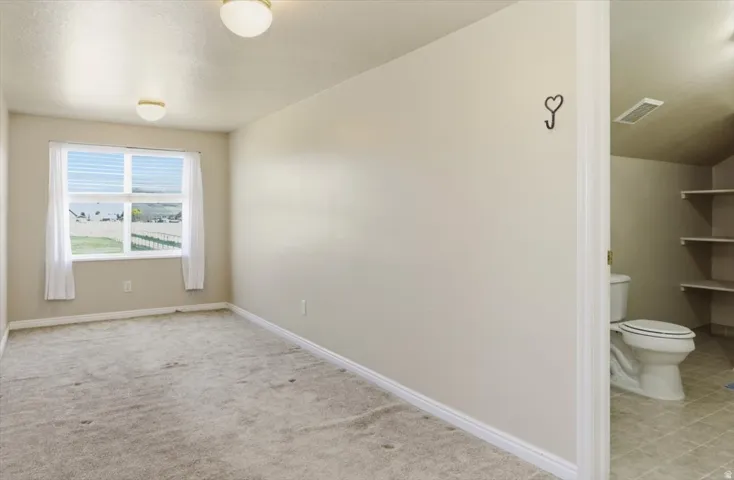 Empty room featuring baseboards and light carpet