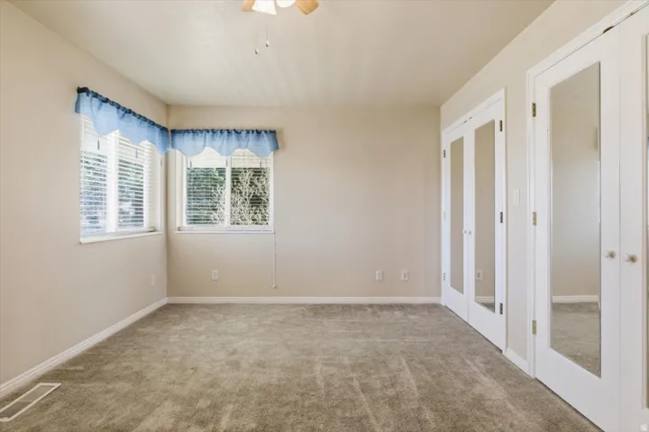 Spare room featuring french doors, carpet flooring, and a ceiling fan