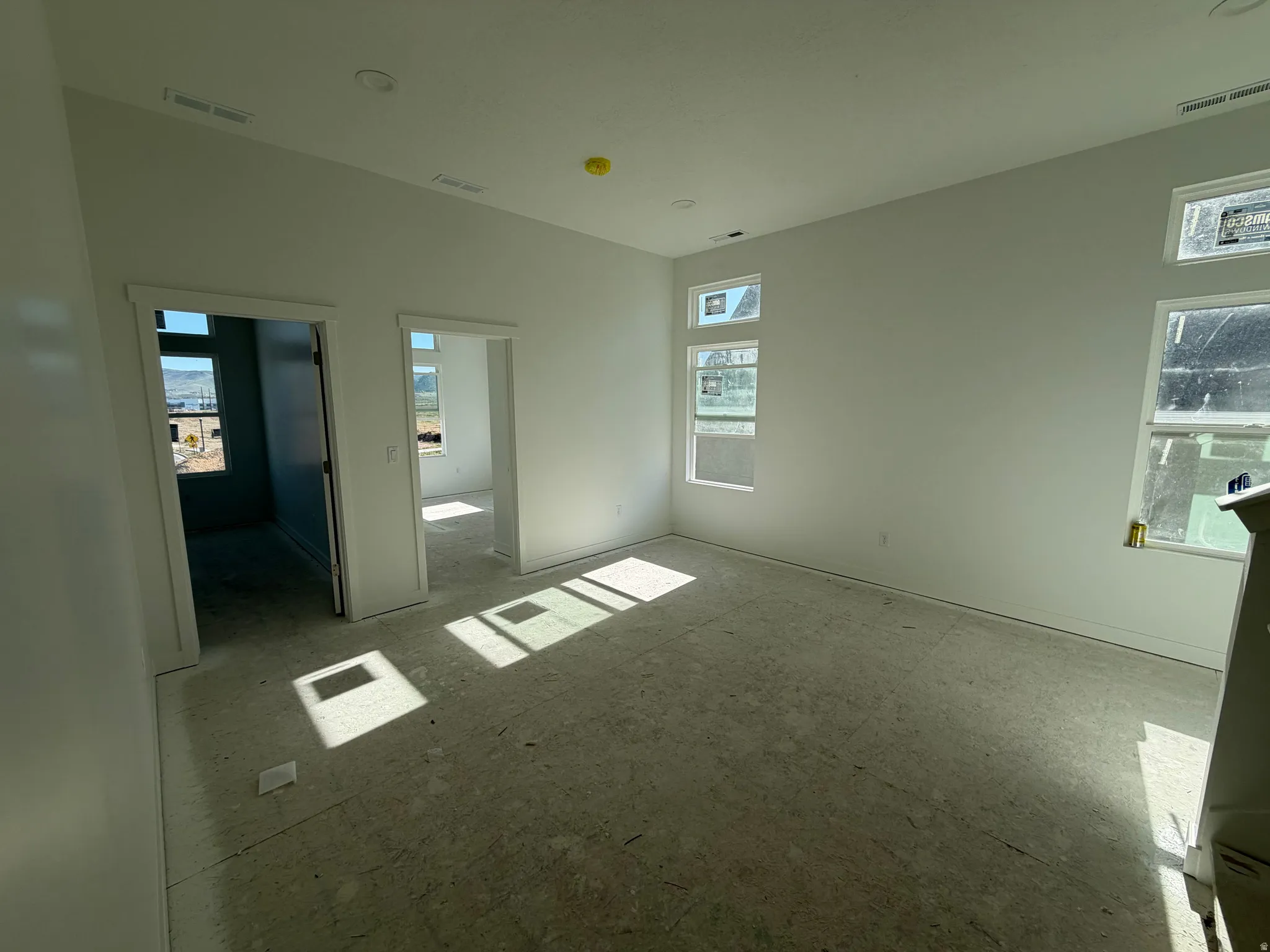 Room with multiple windows, two doorways, and white painted walls