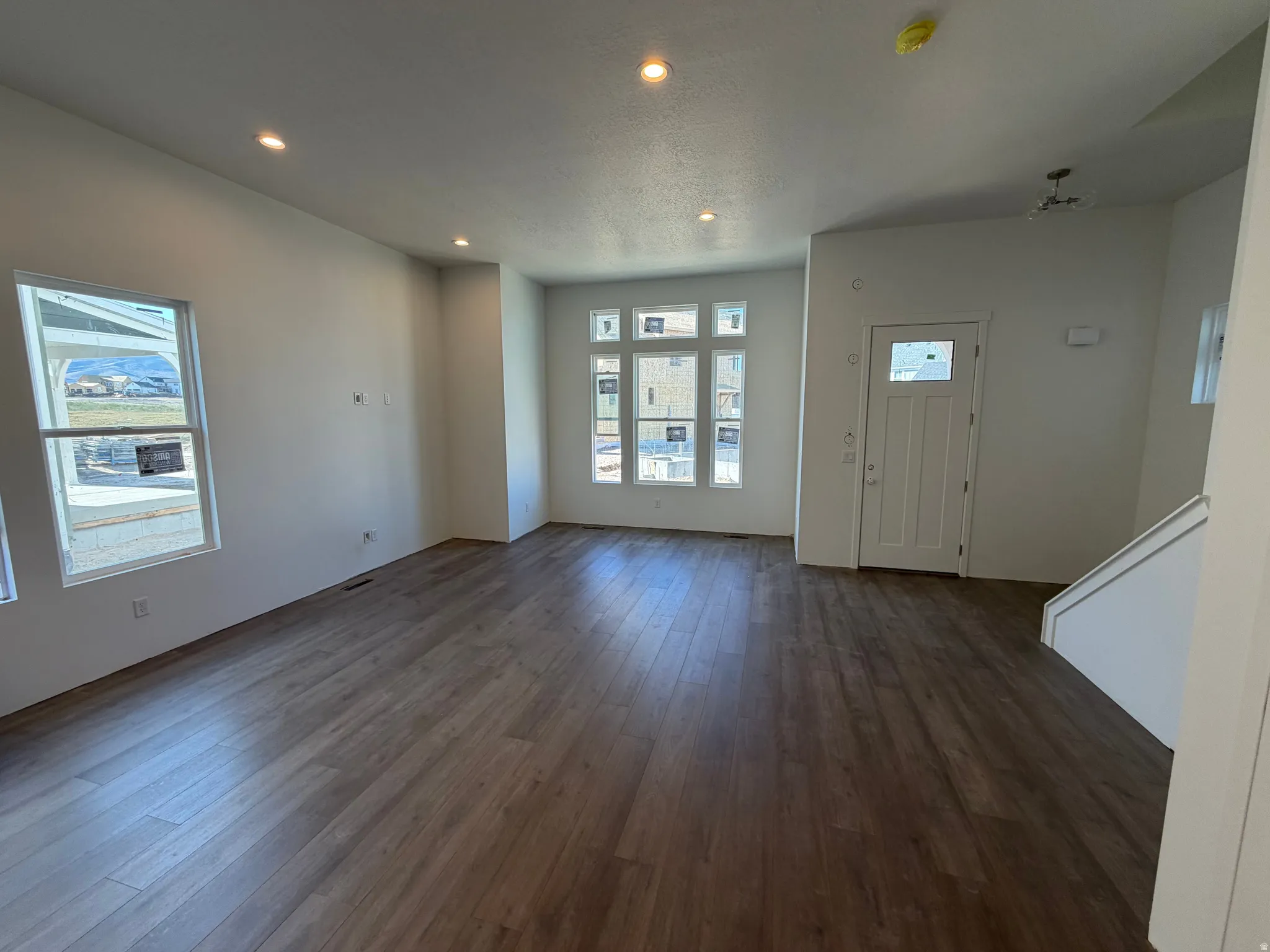 Spacious living area featuring wood-finish flooring, white walls, and recessed lighting