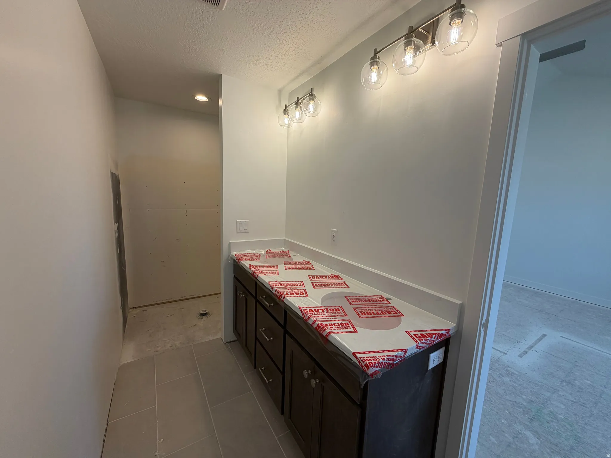 Double vanity with a light-toned countertop, dark wood-finish cabinetry, and a four-light fixture