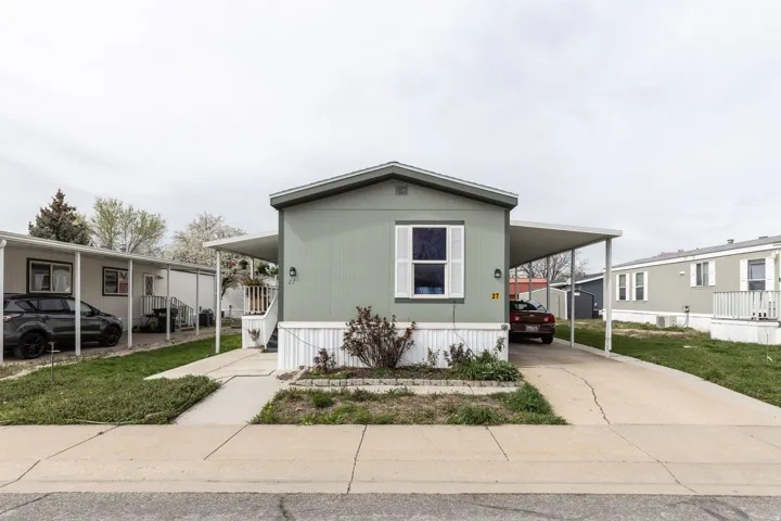 Manufactured / mobile home featuring a carport, a porch, concrete driveway, and a front yard