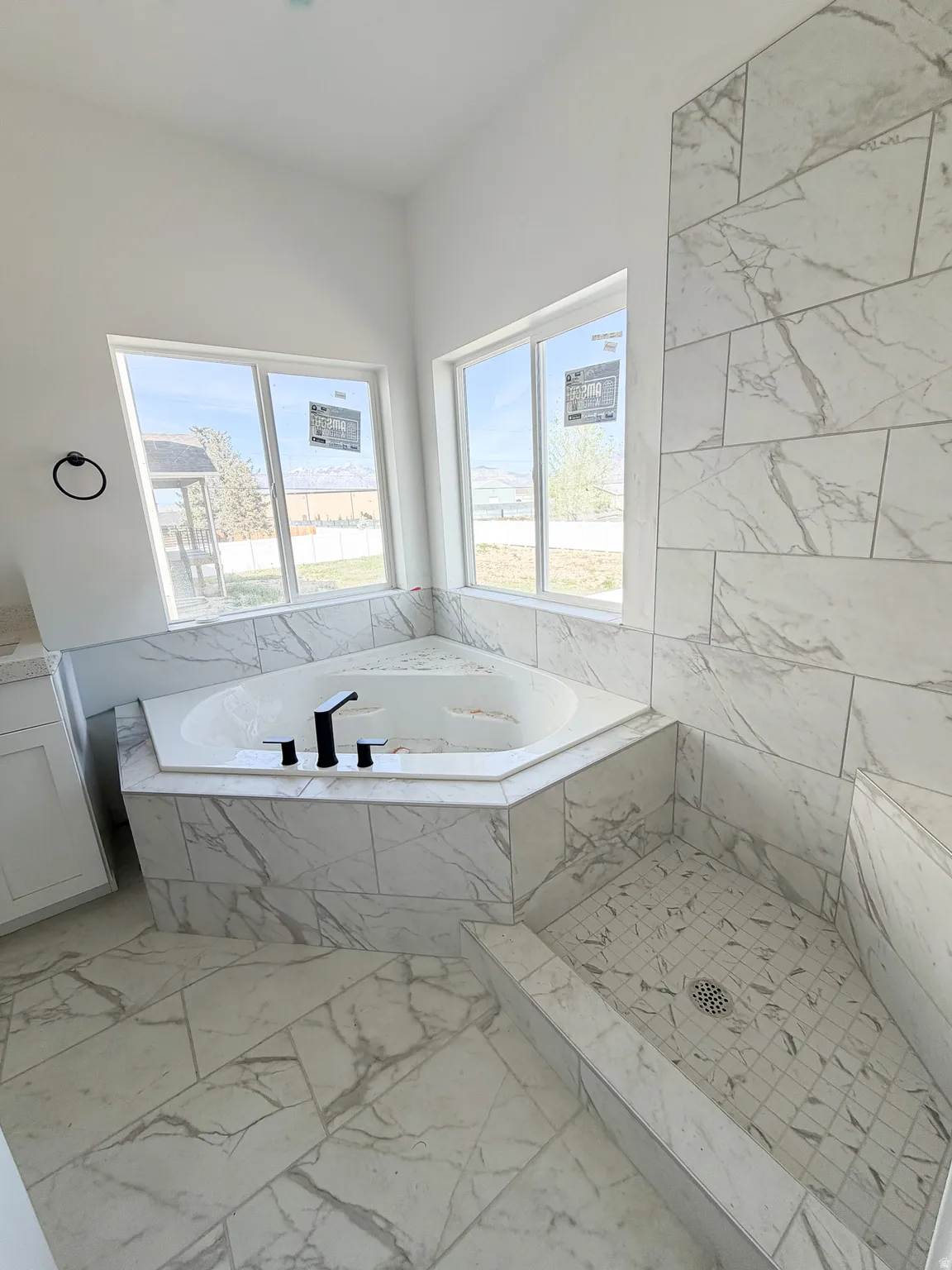 Bathroom featuring a garden tub, marble finish floors, a marble finish shower, and plenty of natural light