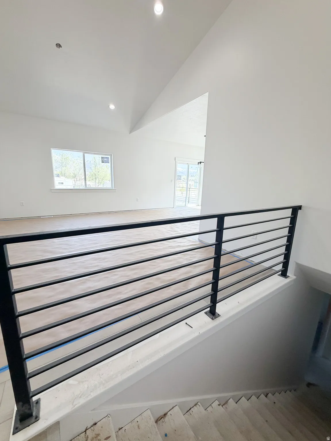 Stairway with recessed lighting, a high ceiling, and wood finished floors