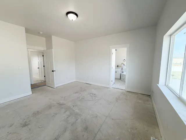 Unfurnished bedroom featuring baseboards and connected bathroom