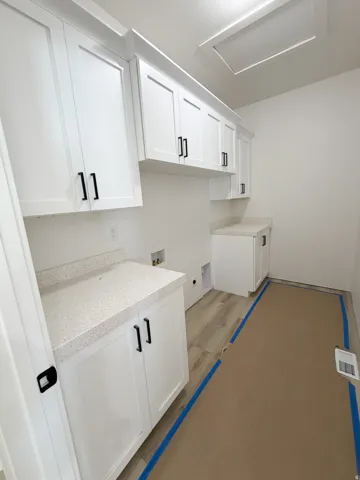 Laundry area with washer hookup, cabinet space, and wood finished floors