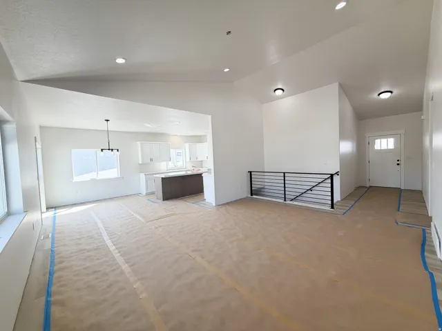 Unfurnished living room with healthy amount of natural light, vaulted ceiling, and recessed lighting