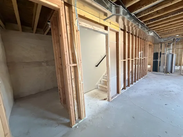 Unfinished below grade area with stairs and gas water heater