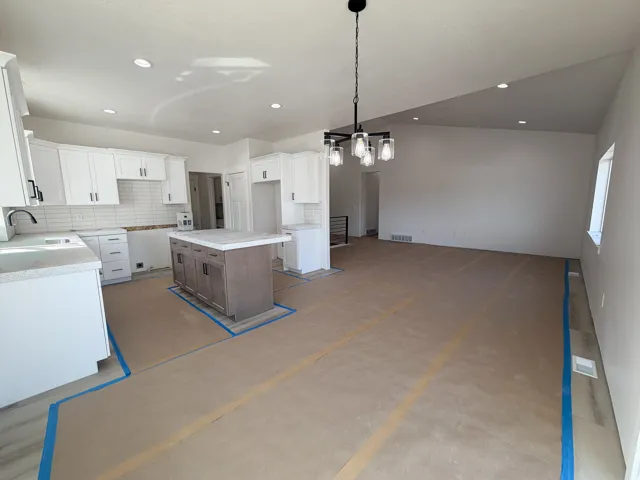Kitchen featuring tasteful backsplash, dual tone cabinets, a center island, pendant lighting, and open floor plan