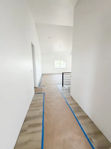 Corridor featuring light wood-style floors and lofted ceiling