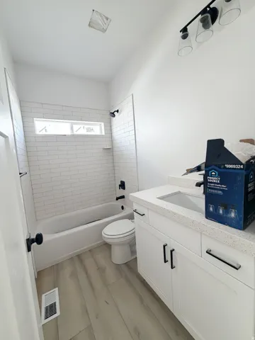 Bathroom featuring vanity, light wood-type flooring, and  shower combination