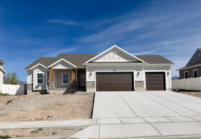 Craftsman house with covered porch, board and batten siding, an attached garage, stone siding, and driveway