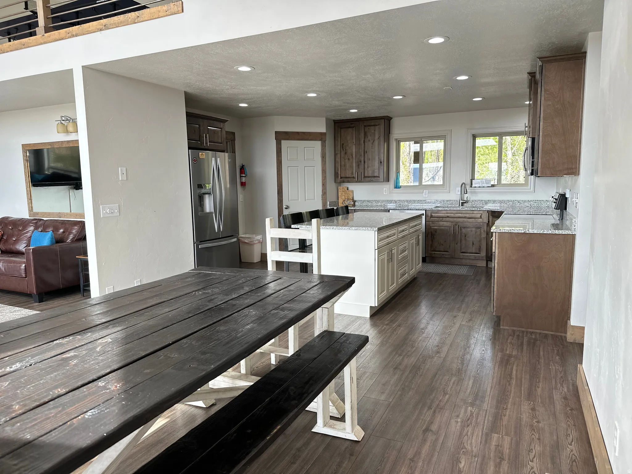 Two tone kitchen with light stone countertops, stainless steel appliances, dark wood-style floors, recessed lighting, and a kitchen island