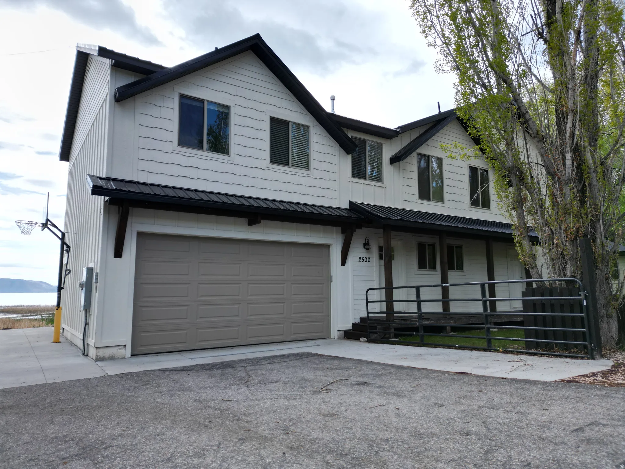 Modern farmhouse style home with a metal roof, an attached garage, covered porch, and driveway