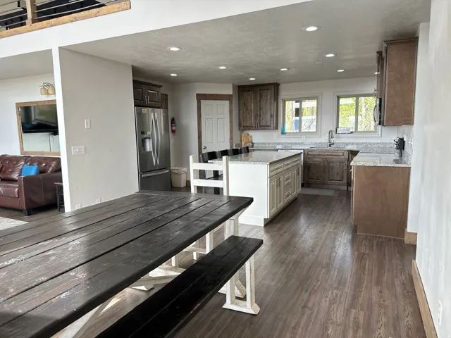 Two tone kitchen with light stone countertops, stainless steel appliances, dark wood-style floors, recessed lighting, and a kitchen island