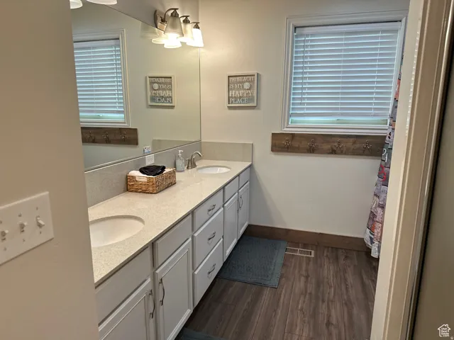 Full bath featuring double vanity and dark wood finished floors