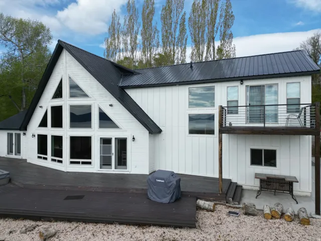 Back of house with board and batten siding, a wooden deck, and a metal roof