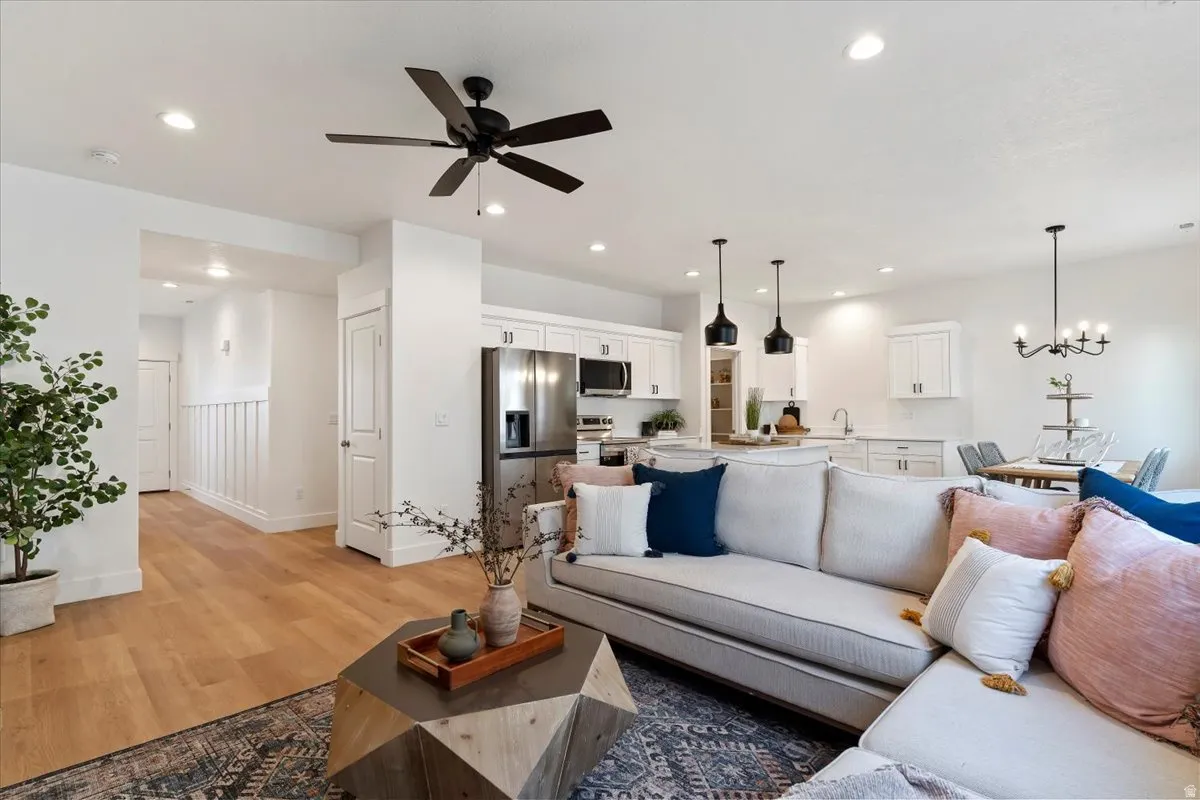 Living room with light wood-type flooring, a ceiling fan, and a chandelier