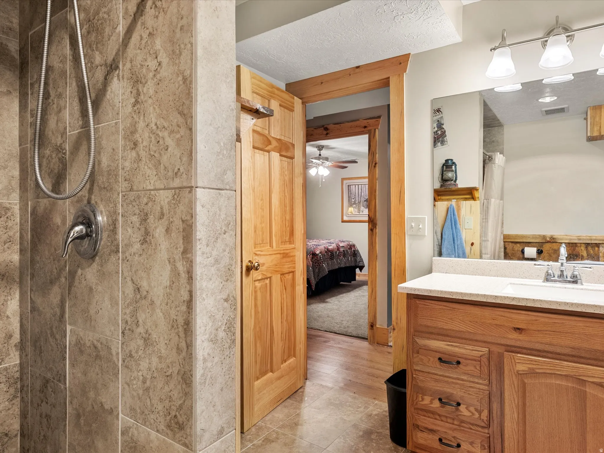 Bathroom with vanity, a tile shower, connected bathroom, a ceiling fan, and light tile patterned floors
