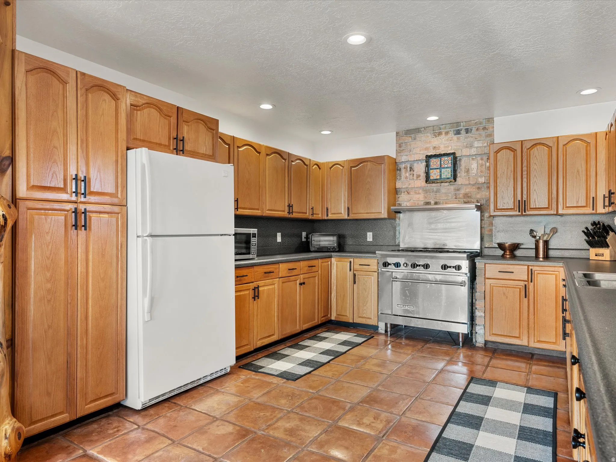 Kitchen with freestanding refrigerator, luxury range, dark countertops, recessed lighting, and tasteful backsplash