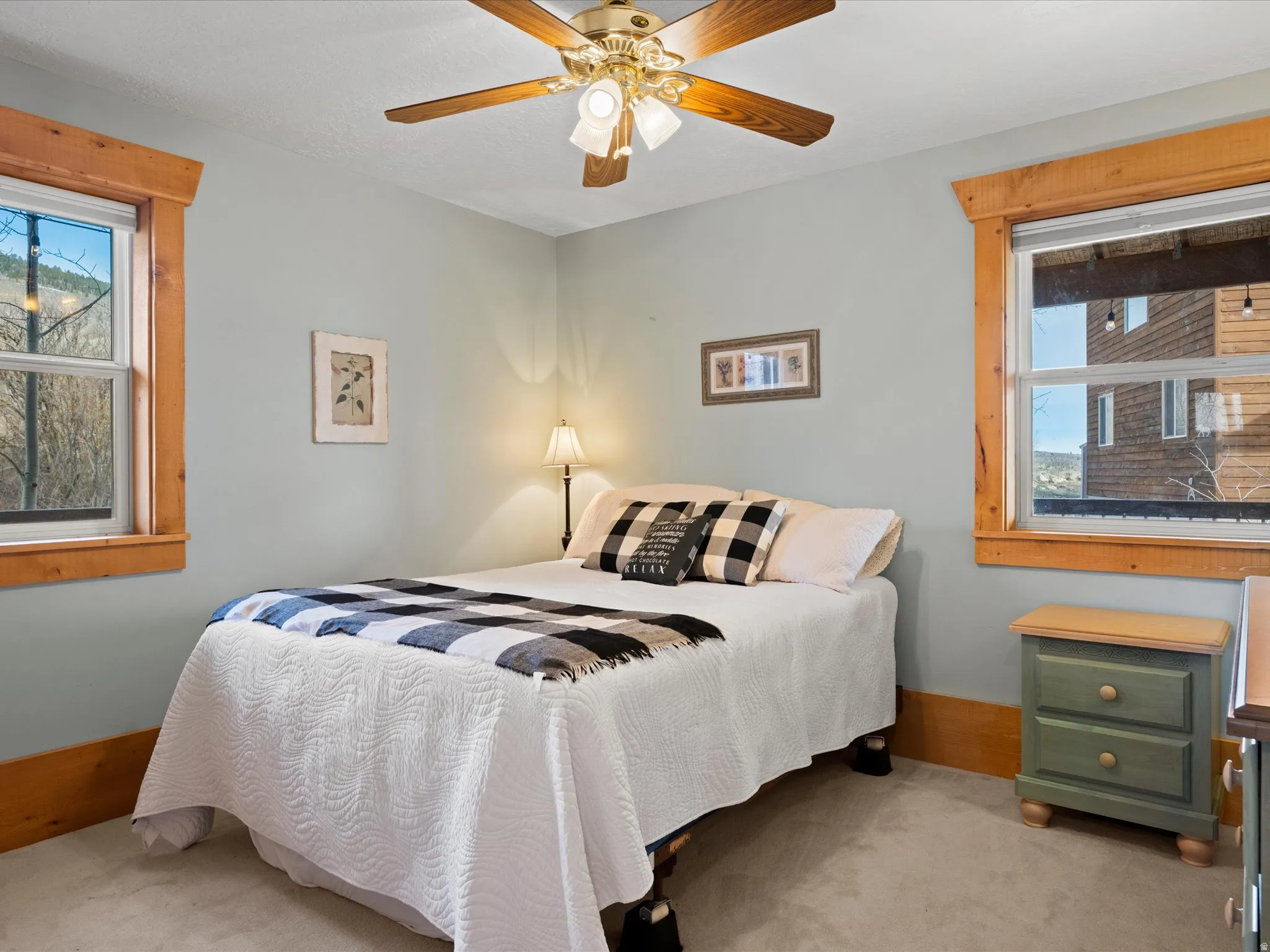 Bedroom featuring multiple windows, light colored carpet, and a ceiling fan