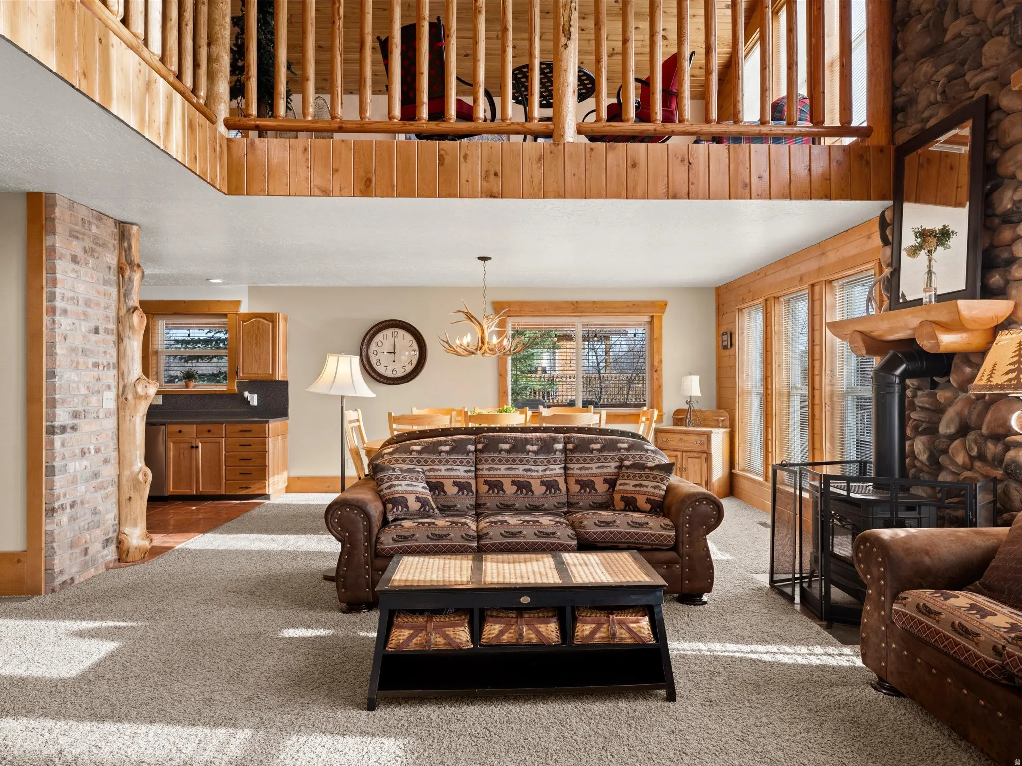Carpeted living room featuring a high ceiling, hanging lights, and a wood stove
