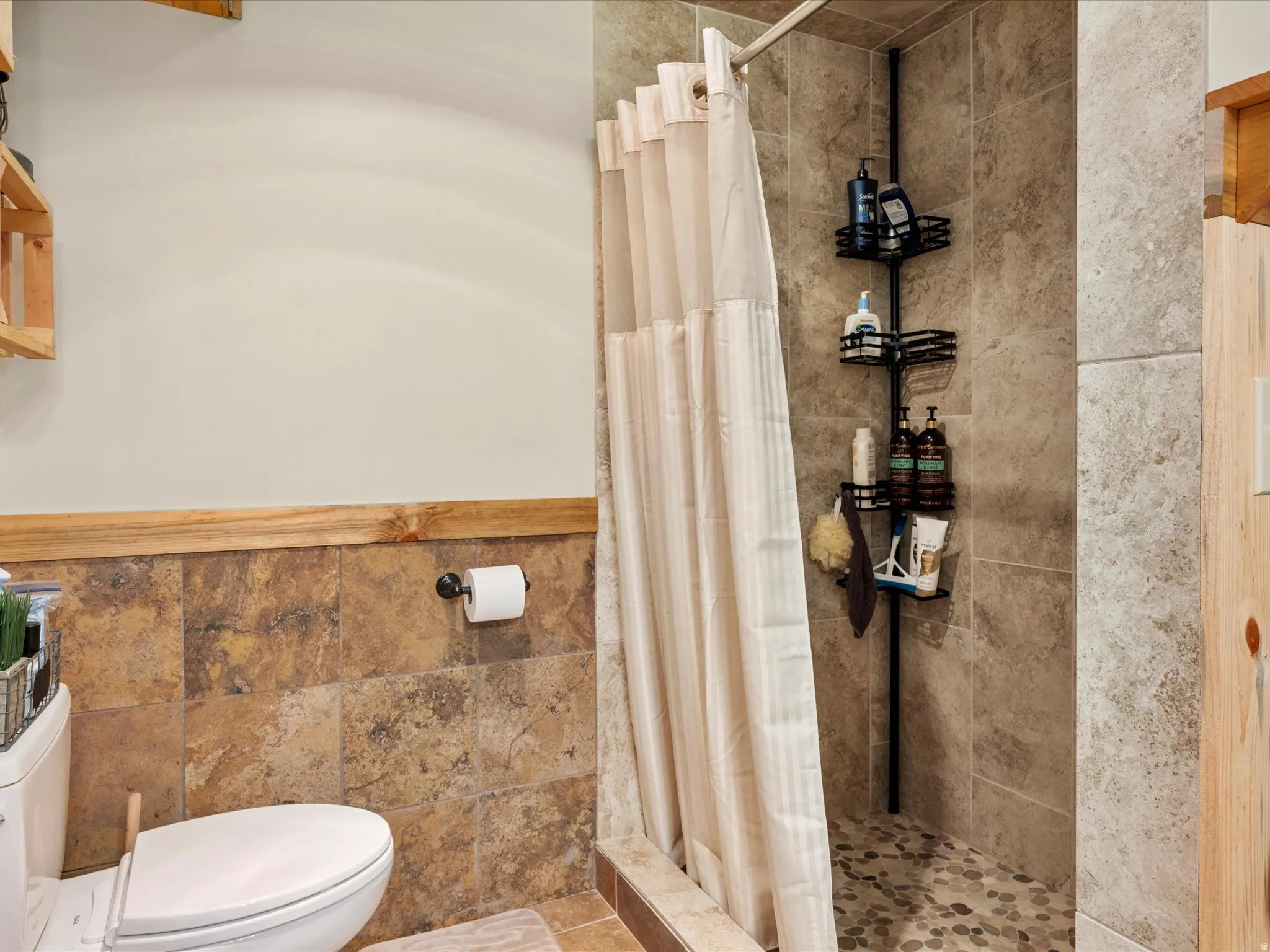 Full bathroom with a shower stall and tile walls