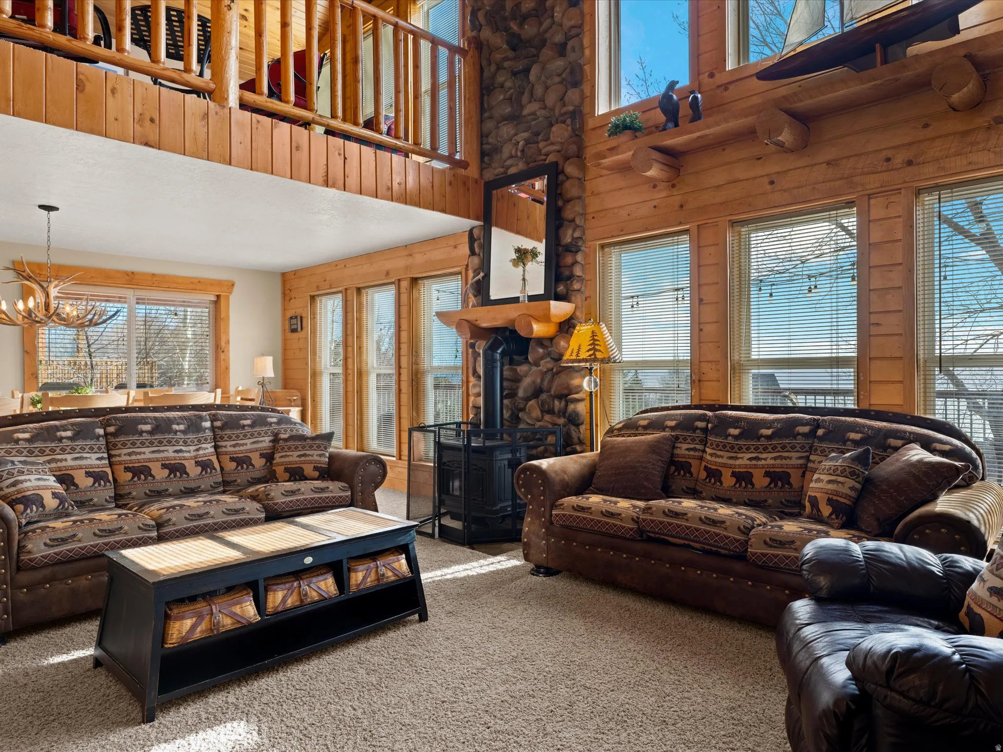 Living area featuring wood walls, carpet, suspended lighting, a wood stove, and a high ceiling