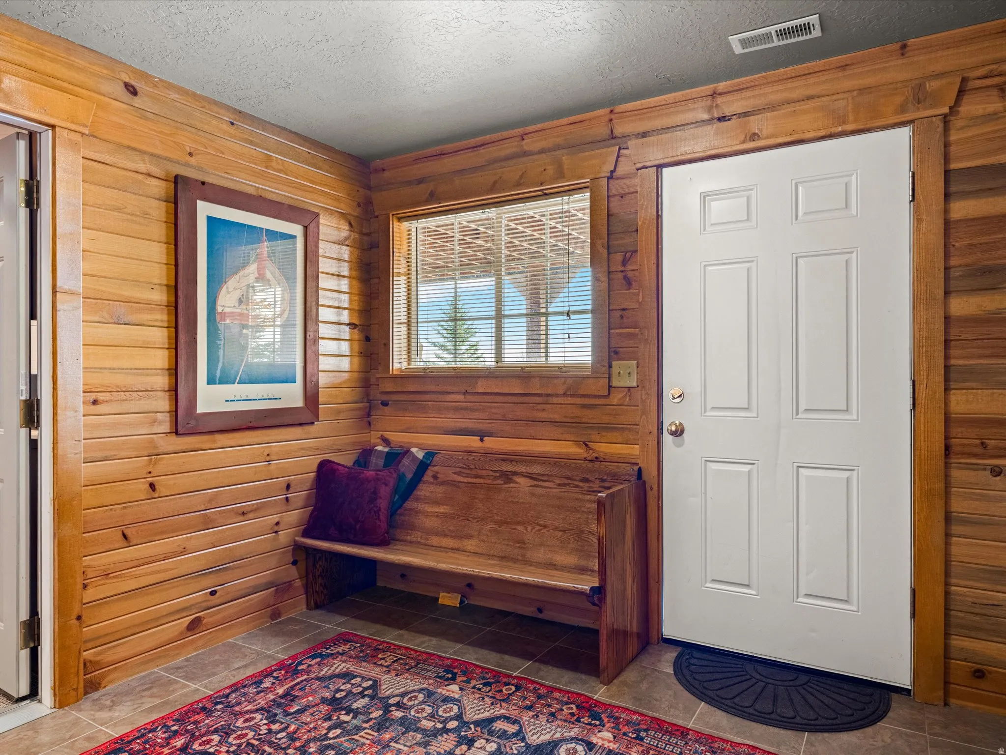 Tiled foyer featuring a textured ceiling and wood walls