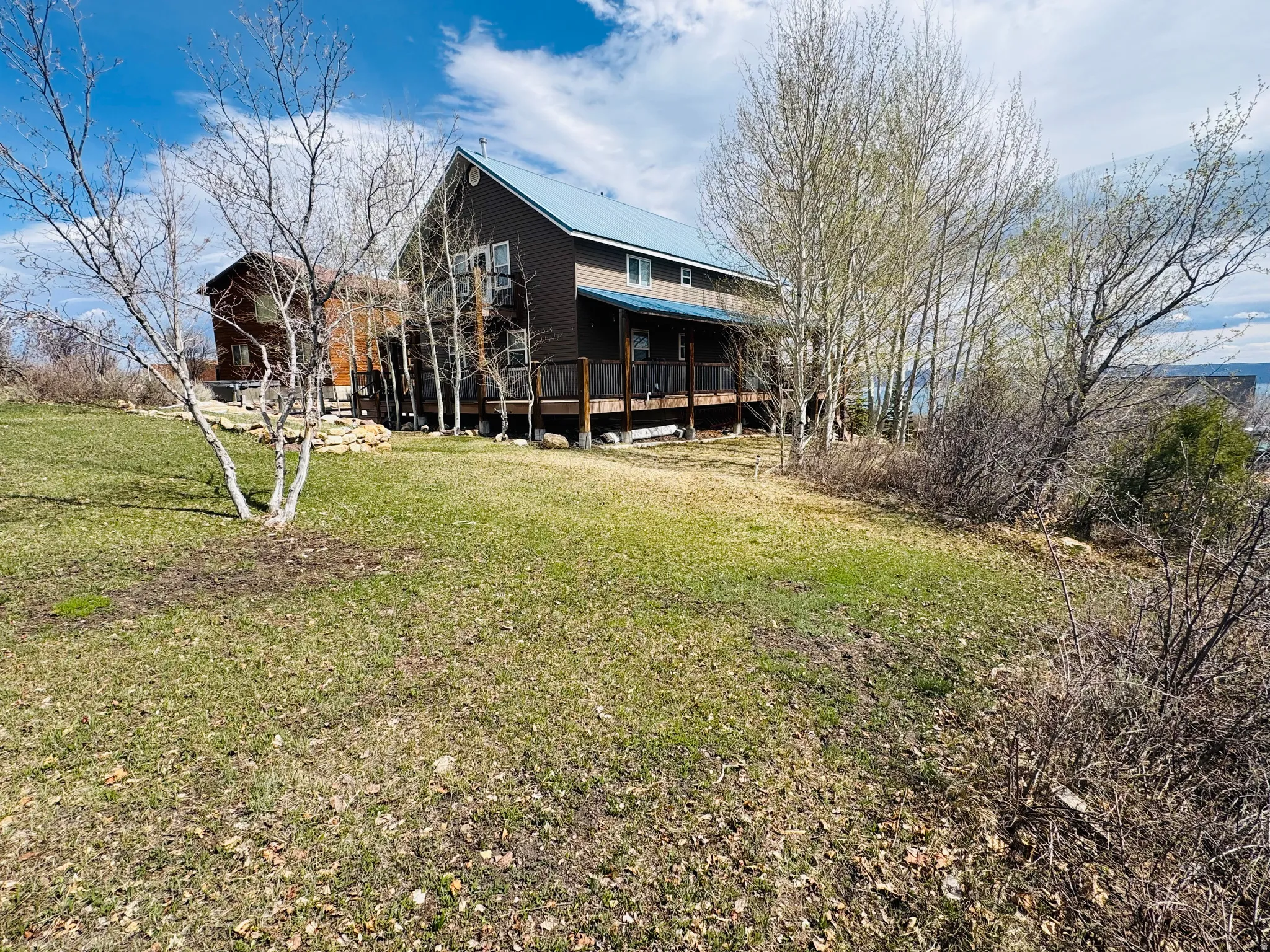 Back of house with a metal roof, a yard, and a wooden deck