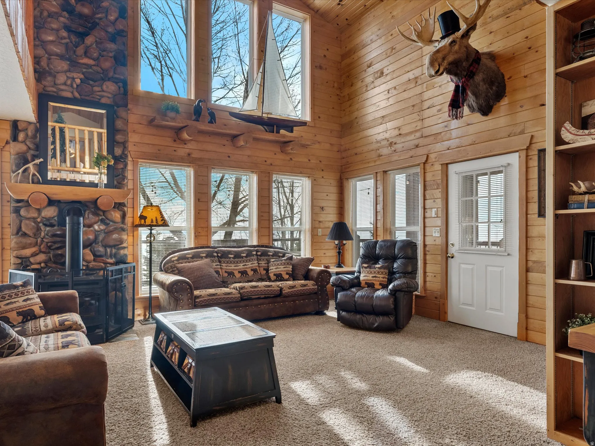 Carpeted living room with a wood stove, a high ceiling, and wooden walls