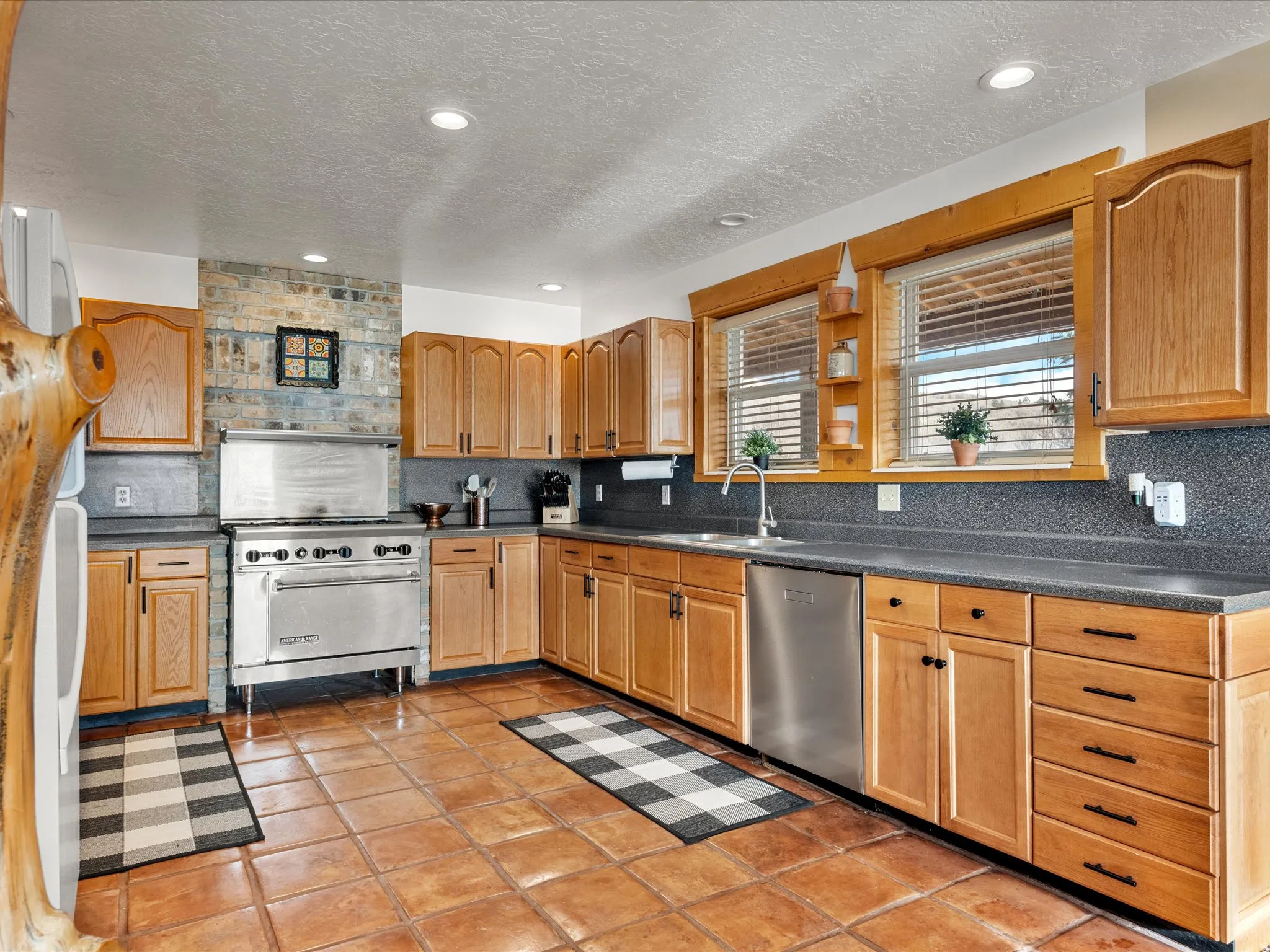 Kitchen featuring dark countertops, stainless steel appliances, backsplash, a textured ceiling, and recessed lighting