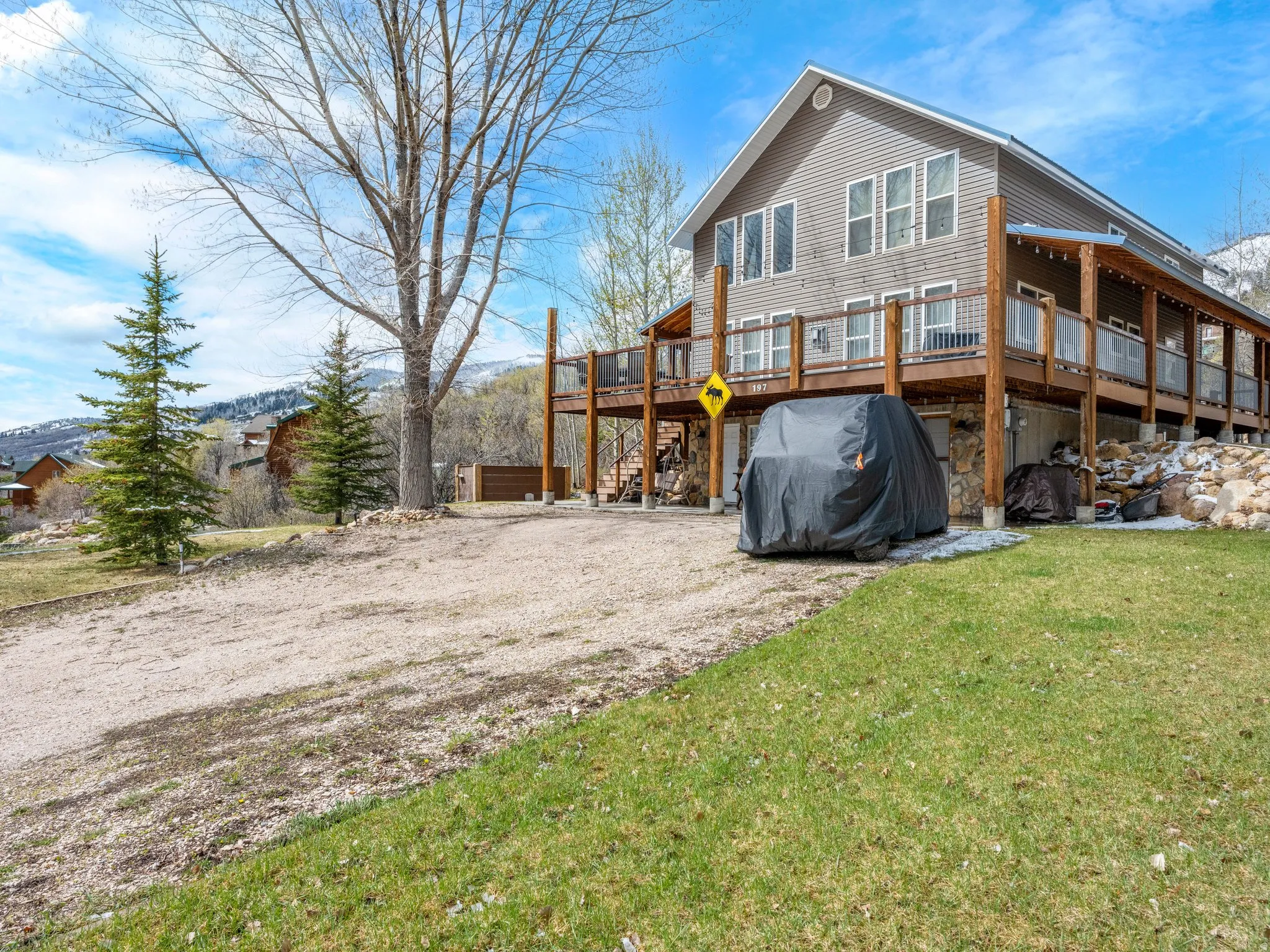 Back of house featuring a deck, a yard, and driveway